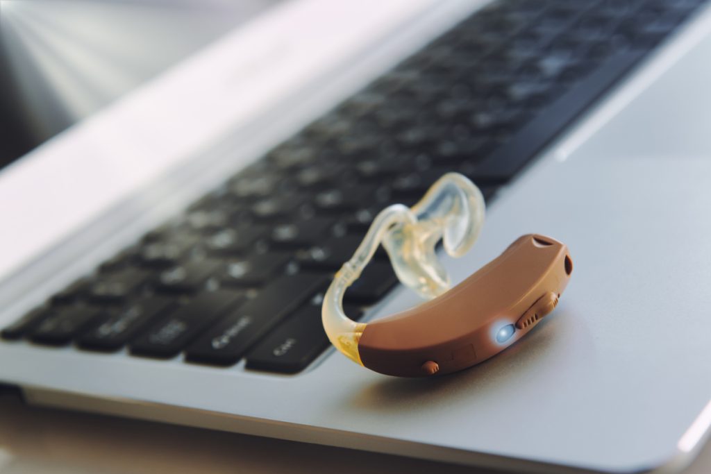Hearing aid device on laptop, work in office for deaf people